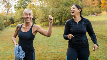 Two woman laughing in the park while exercising.  