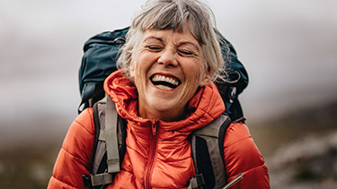 Woman wearing a hiking backpack smiles.  