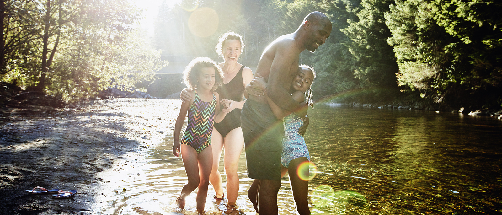 Family playing in the water by the river.