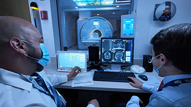 Two doctors discuss results on a computer screen in front of them.