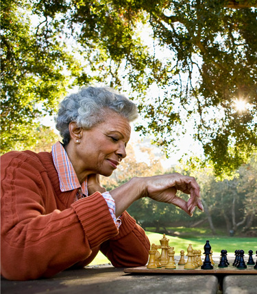 Two women enjoying a game of chess at the park.